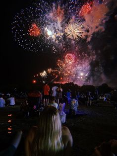 people watching fireworks in the night sky with bright lights on their head and arms,