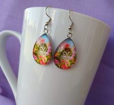 Cute, Adorable Kitten Among Flowers Handmade Cat Themed Glass Earrings A purrfect gift for any animal lover or cat lover. Chic Bold and Unique. Measures 0.98 inches in length and 0.70 inches in width. Comes with First Class Free shipping.. Colors may vary due to monitor and lighting differences. Cat Design Earrings With Cat Ears For Gifts, Cat Design Earrings With Cat Ears Shape For Gift, Cute Cat Design Adjustable Earrings, Cat Design Earrings With Cat Ears, Adjustable Cute Cat Design Earrings, Cute Adjustable Cat Design Earrings, Cute Hypoallergenic Cat Ears Jewelry, Cute Hypoallergenic Teardrop Earrings, Hypoallergenic Cat Ears Jewelry For Gift