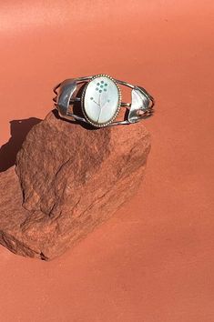 Zuni Turquoise Mother of Pearl Inlay Flower Cuff | Native American Sterling Flower Cuff This pretty cuff is in excellent vintage condition. Handcrafted in the late 1960s or early 1970s, the cuff features attractive twisted sterling wire construction and a large central setting flanked by sterling abstract feathers/leaves. The piece is set with a classic Zuni flower design made from beautiful iridescent mother of pearl and snake eye turquoise. 6 1/4" inner circumference including 1 3/8" opening (fits wrists up to 6 7/8") top is 1 3/8" Vintage Adjustable Cuff Bracelet For Spring, Adjustable Vintage Cuff Bracelet For Spring, Handmade Vintage Bracelets For Spring, Vintage Flower Bracelets For Spring, Vintage Blue Cuff Bracelet, Flower Cuff, Mother Of Pearl Inlay, Snake Eyes, Pearl Inlay