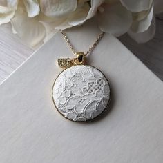 This vintage lace necklace is the perfect gift for those that love a timeless and elegant style. The white floral lace from the 1950s evokes a sense of delicate beauty, with a background of shiny cream color satin that highlights the intricate lace design. It's set in a gold metallic metal alloy pendant, with a dainty gold stainless steel chain that measures 22 inches in total length. Letter charm: The finishing touch is the capital letter initial charm that adorns the top of the pendant. This charm offers the perfect way to make this necklace a thoughtful and personalized gift. Gift box: The necklace will be packaged in a stylish, branded gift box, ready to be presented with love and care.  Gift notes:  Write a personalized note to your loved one at checkout, and it will be printed on dec White Feminine Jewelry For Anniversary, Elegant Vintage Charm Necklace For Anniversary, White Lace Necklace For Wedding, Elegant Vintage Charm Necklace For Keepsakes, White Dainty Necklace With Vintage Charm, White Filigree Round Pendant Necklace, Dainty White Necklace With Vintage Charm, Vintage White Necklaces For Wedding, Elegant Crochet Lace For Ceremonies