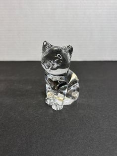 a glass cat figurine sitting on top of a black table next to a white wall