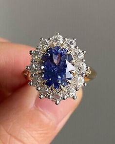 a blue and white diamond ring in someone's hand