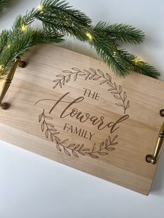 a wooden cutting board with the words'the family'engraved on it next to christmas tree branches