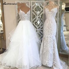 two wedding dresses on mannequins in front of a mirror, one is white and the other is ivory