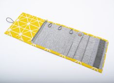 a yellow and gray place mat with two hooks on each side, sitting on a white surface