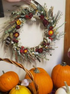 a wreath is hanging on the wall next to some pumpkins and other autumn decorations