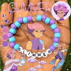 a hand holding a bracelet with cartoon characters on it and the words glimmer spelled out