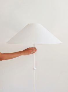 a person holding a white lamp on top of a table