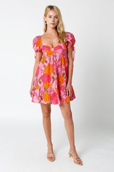 STYLE INFORMATION: Throw on the Jessie Pink Floral Babydoll Mini Dress and meet your friends for brunch! Woven fabric in a pink, yellow, and orange floral print, shapes a sweetheart neckline, empire bodice, and puffy short sleeves with ties and elasticized shoulders. Babydoll silhouette continues to a flirty mini skirt with ruffle hem. Lined. DETAILS & CARE: Cotton. Machine wash cold. Imported. SHIPPING: Orders are processed within 1-2 business days. Packages are shipped out Monday-Friday, holid Pink Puff Sleeve Mini Dress For Garden Party, Summer Floral Puff Sleeve Dress With Sweetheart Neckline, Pink Puff Sleeve Dress With Sweetheart Neckline For Brunch, Pink Puff Sleeve Dress With Sweetheart Neckline, Pink Puff Sleeve Dress With Sweetheart Neckline And Ruffles, Summer Puff Sleeve Dress With Empire Waist For Brunch, Summer Brunch Puff Sleeve Dress With Empire Waist, Casual Pink Puff Sleeve Dress For Garden Party, Pink Puff Sleeve Dress With Sweetheart Neckline For Summer