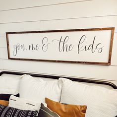 a sign that says you me and the kids above a bed with pillows on it