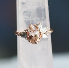 a close up of a ring on top of a clear piece of glass with an orange and white diamond in the middle