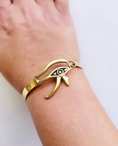 Brass gold plated semi-cuff with side closure. Diameter is 2.2 inches, width is .25 inches. Very lightweight. Egyptian god Eye of Horus design. Made in Egypt. Adjustable Symbolic Gold Cuff Bracelet, Gold Symbolic Bangle Cuff Bracelet, Symbolic Gold Bangle Cuff Bracelet, Adjustable Gold-tone Brass Cuff Bracelet, Adjustable Gold-tone Metal Cuff Bracelet, Gold-tone Cuff Bracelet As Gift, Gold-tone Cuff Bracelet Gift, Horus Design, God Eye