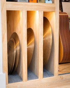 guitars are lined up in a wooden storage unit with plywood panels on the sides