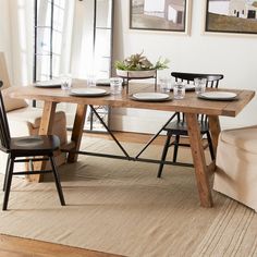 a dining room table with plates and glasses on it, in front of a couch