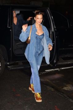 a woman in blue denim outfit stepping out of a car