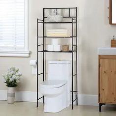 a white toilet sitting next to a wooden cabinet in a bathroom with a sink and mirror