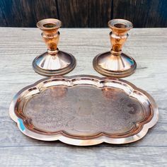 two silver candlesticks sitting on top of a metal tray