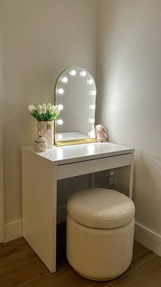 a vanity table with a stool and lighted mirror