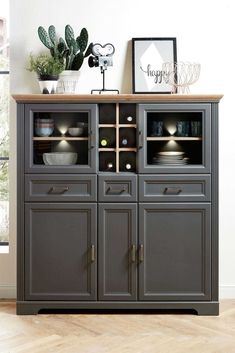 a large gray cabinet with glass doors and shelves on the top, next to a potted plant