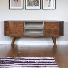 a wooden entertainment center with two pictures on the wall above it and a rug in front of it