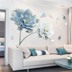 a living room with white furniture and blue flowers on the wall