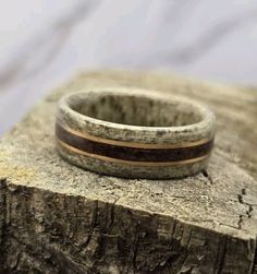 a wooden ring sitting on top of a piece of wood with a black and brown stripe