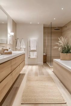 a large bathroom with wooden floors and white walls, along with two sinks on either side of the bathtub