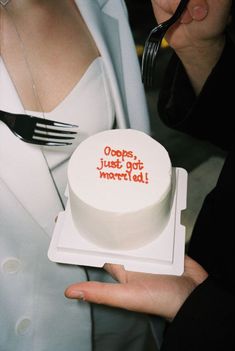 a woman holding a cake with writing on it and a fork in the other hand