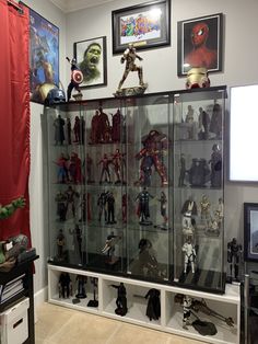 a display case full of action figures and toys in a room with pictures on the wall