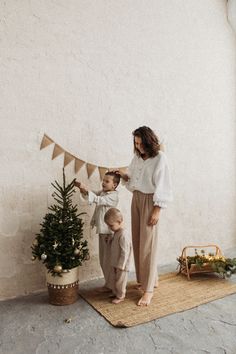 a woman and child decorating a small christmas tree with bunting on the side