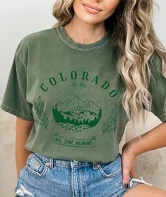 "This unisex t-shirt is perfect for the hiking lover in your life who adores the Colorado Mountains. Featuring a beautiful design of trees and the iconic Rocky Mountains, it's a great choice for anyone who loves the outdoors. Whether you're planning a family trip to Colorado or just want a stylish souvenir to remember your travels, this Colorado Shirt is a must-have. Made with high-quality materials, this shirt is both comfortable and durable, making it perfect for any adventure. Show off your l Green T-shirt For Outdoor Activities, Casual Slogan T-shirt For Outdoor, Crew Neck T-shirt With Letter Print For Hiking, Green Graphic Tee For Outdoor Activities, Green Graphic Tee For Outdoor, Green T-shirt With Letter Print For Outdoors, Green T-shirt With Letter Print For Outdoor Activities, Green Letter Print T-shirt For Outdoor Activities, Green Graphic Print T-shirt For Hiking