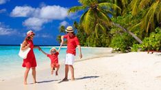 a man and two children are walking on the beach with palm trees in the background