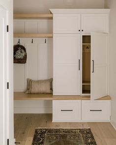 an empty room with white cabinets and wood flooring on the walls, along with a rug