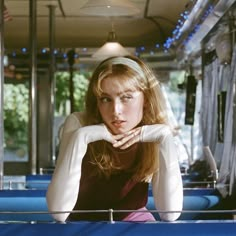 a woman sitting on top of a bus next to a blue table with chairs in front of her