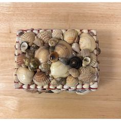 there are many seashells in the small box on the wooden table and it is hard to see