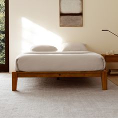 a bed sitting in the middle of a bedroom next to a table with a lamp on it