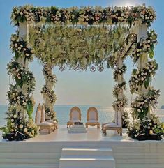 an outdoor wedding set up with white flowers and greenery on the aisle, overlooking the ocean