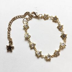 One bracelet, featuring a row of tiny cubic zirconia-filled star shaped gold tone plated brass chain links. Bracelet is adjustable between approximately 6" - 9" long, with a lobster clasp and a gold tone star charm. You will receive one from the photos or identical from the same batch. Adjustable Gold Chain Bracelet With Star Charm, Gold Metal Bracelets With Star Charm, Gold Metal Bracelet With Star Charm, Gold Metal Chain Bracelet With Star Charm, Adjustable Gold Star-shaped Chain Bracelet, Gold Star Charm Chain Bracelet, Adjustable Gold Star Chain Bracelet, Gold Bracelet With Star Charm, Gold Bracelet Jewelry With Star Charm