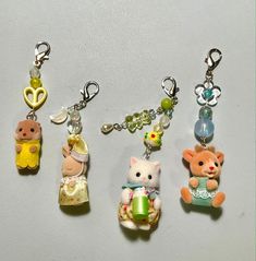 four different key chains with small animals and other items attached to them on a white surface