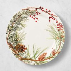 a white plate with pine cones and berries on it, sitting on a marble surface