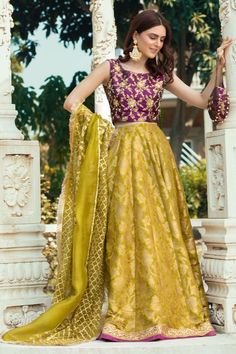 a woman in a yellow and purple lehenga with her hands on her hips