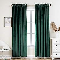 a green curtain hanging in front of a window with white furniture and decor on the floor