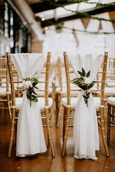 the chairs are decorated with white linens and greenery