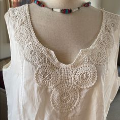 a white top with crochet and beads on it