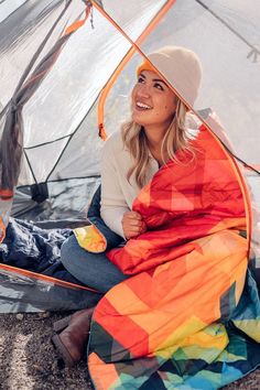 a woman sitting in a tent with a colorful blanket