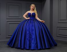 a woman in a blue ball gown posing for the camera with her hands on her hips