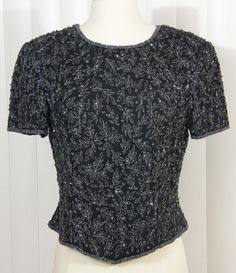 Simply beautiful black  & silver beaded sparkling short sleeved blouse. Black silk, fully lined, with silver threaded design and black jet glass beads.  This top is stunning - dress it up or wear it with your favorite pair of skinny jeans to show off your own classy style. Small shoulder pads and full back zipper  Stated size: PM Bust: 19" Shoulders: 17" Hemline: 18" Shoulder to Hem front or back: 19"  Well Kept, Good Vintage Condition, No damage Sold as is, All sales final... please convo us if Papell Boutique, Sparkle Shorts, Short Sleeved Blouse, Black Jet, Greensboro Nc, Classy Style, Blouse Black, To Shine, Stunning Dresses