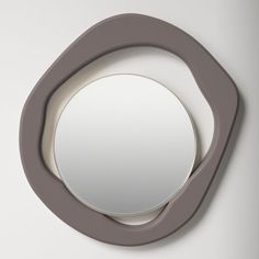 a round mirror mounted to the side of a wall next to a white wall with a gray frame