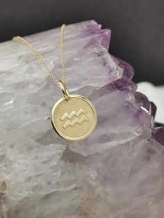 a gold zodiac sign necklace sitting on top of a rock