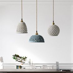 three pendant lights hanging over a dining room table